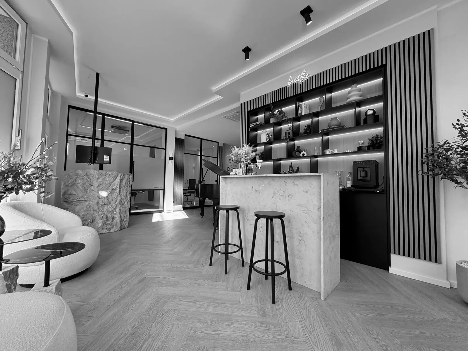 Lounge mit Marmortresen, beleuchteter Regalwand und Flügel