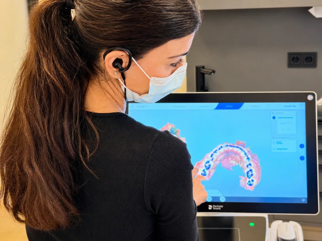 Over-the-shoulder view of a digital dental arch on a monitor